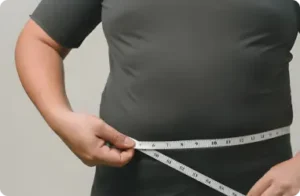 Patient measuring waist circumference as part of a primary care service assessment.